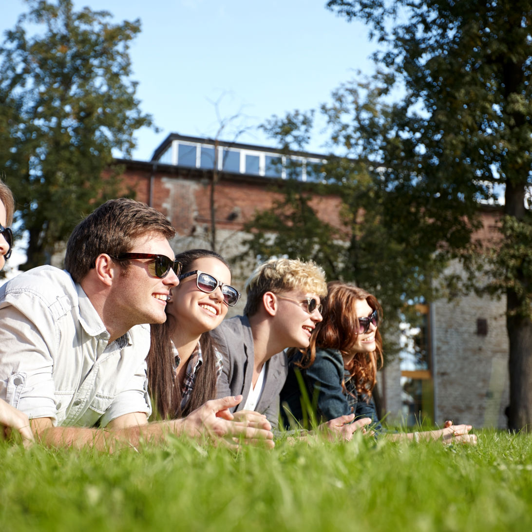 Foto af en gruppe unge mennesker der ligger på en græsplæne