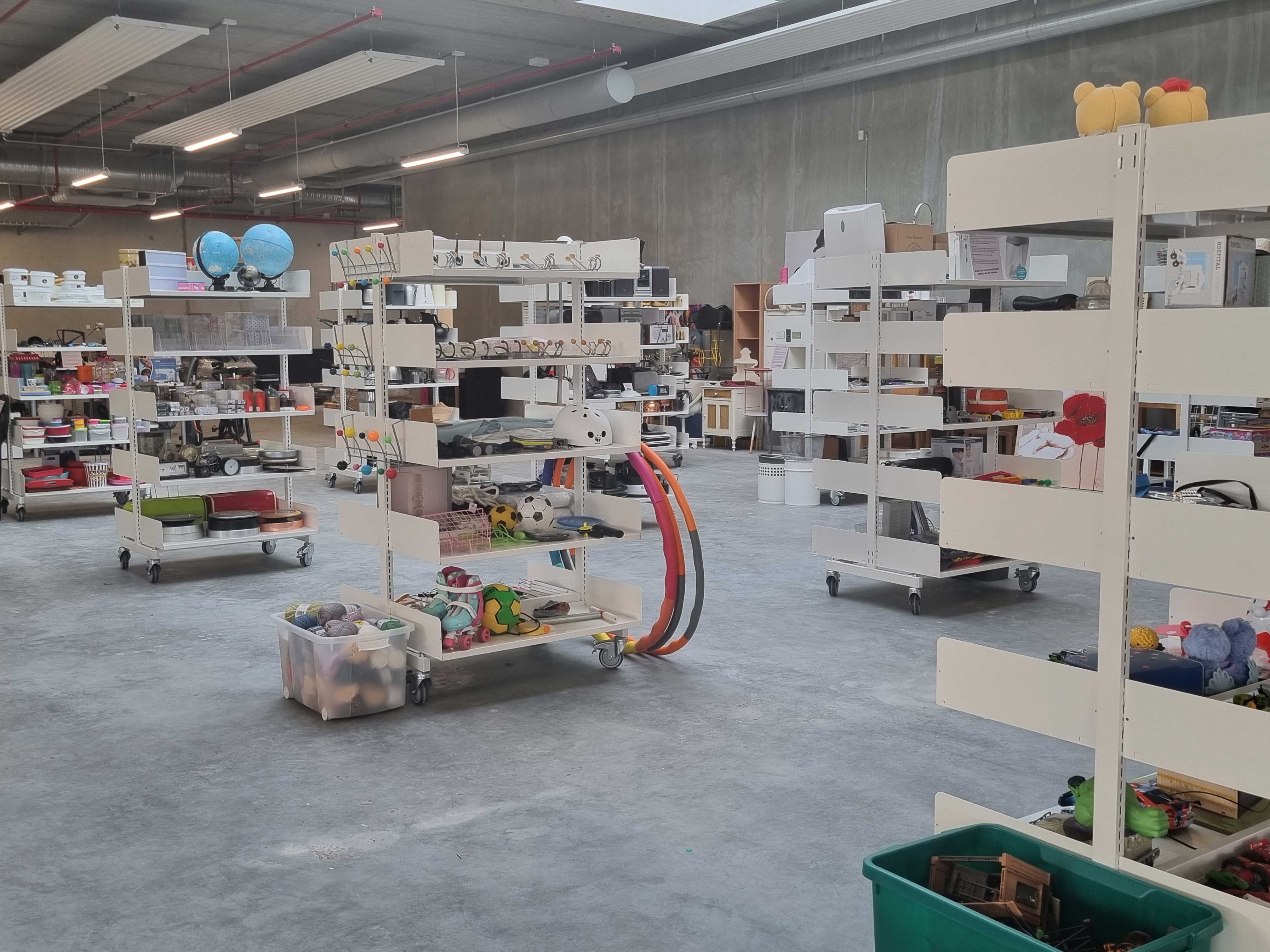 Foto af genbrugsbutikken på RessourceCenter Vejle. Rummet er fyldt med hylder, der indeholder forskellige genbrugsvarer som køkkenudstyr, legetøj, bøger og andre brugte effekter, der er gratis for borgere at tage med hjem