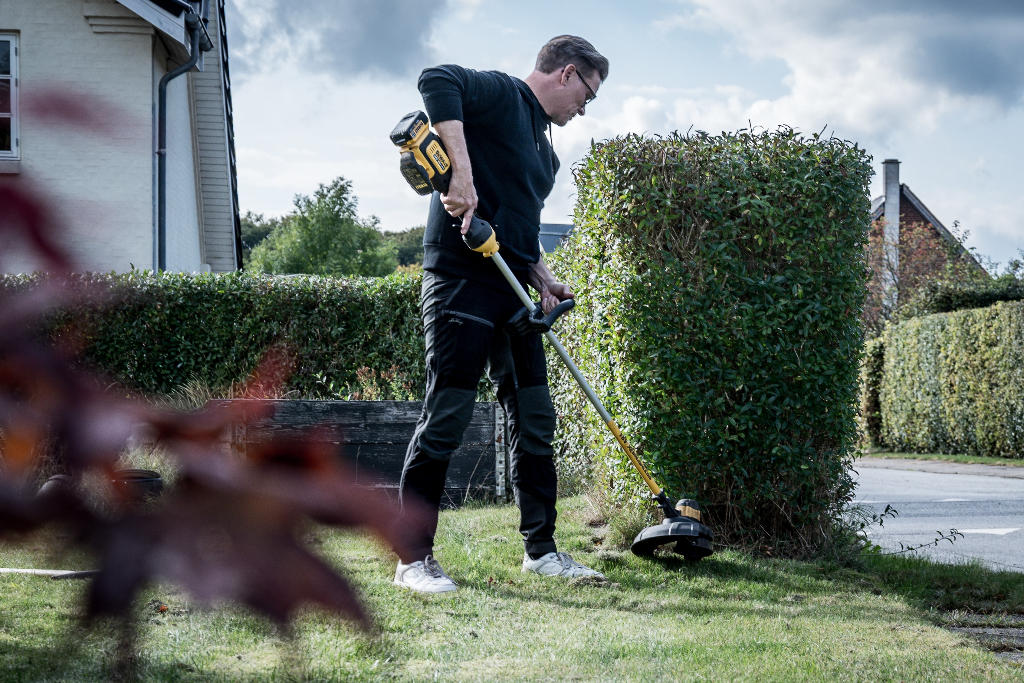 Tomas arbejder med en græstrimmer i forhaven.