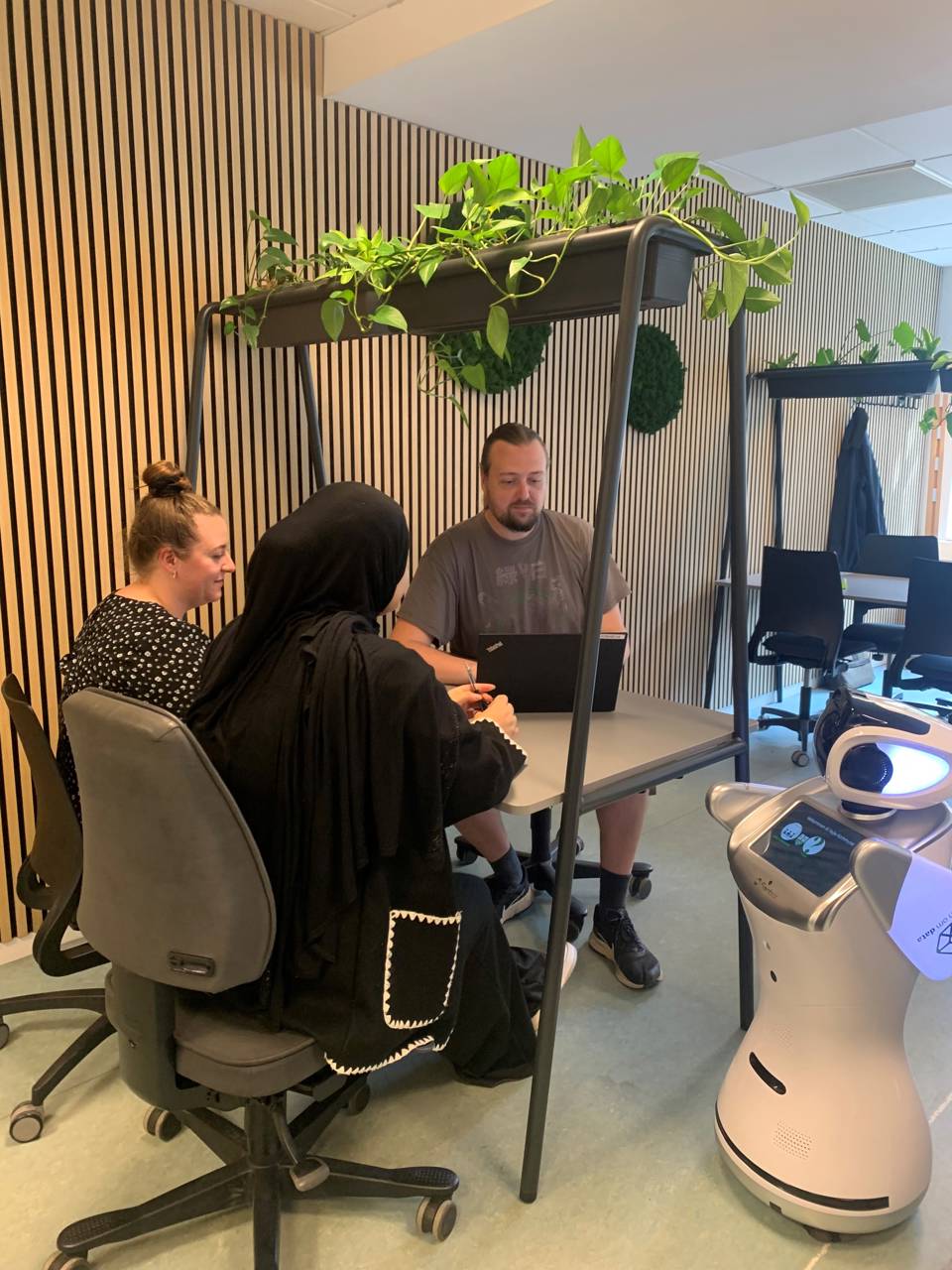 3 elever har gruppearbejde på deres skoleophold på Campus Vejle siddende ved et bord