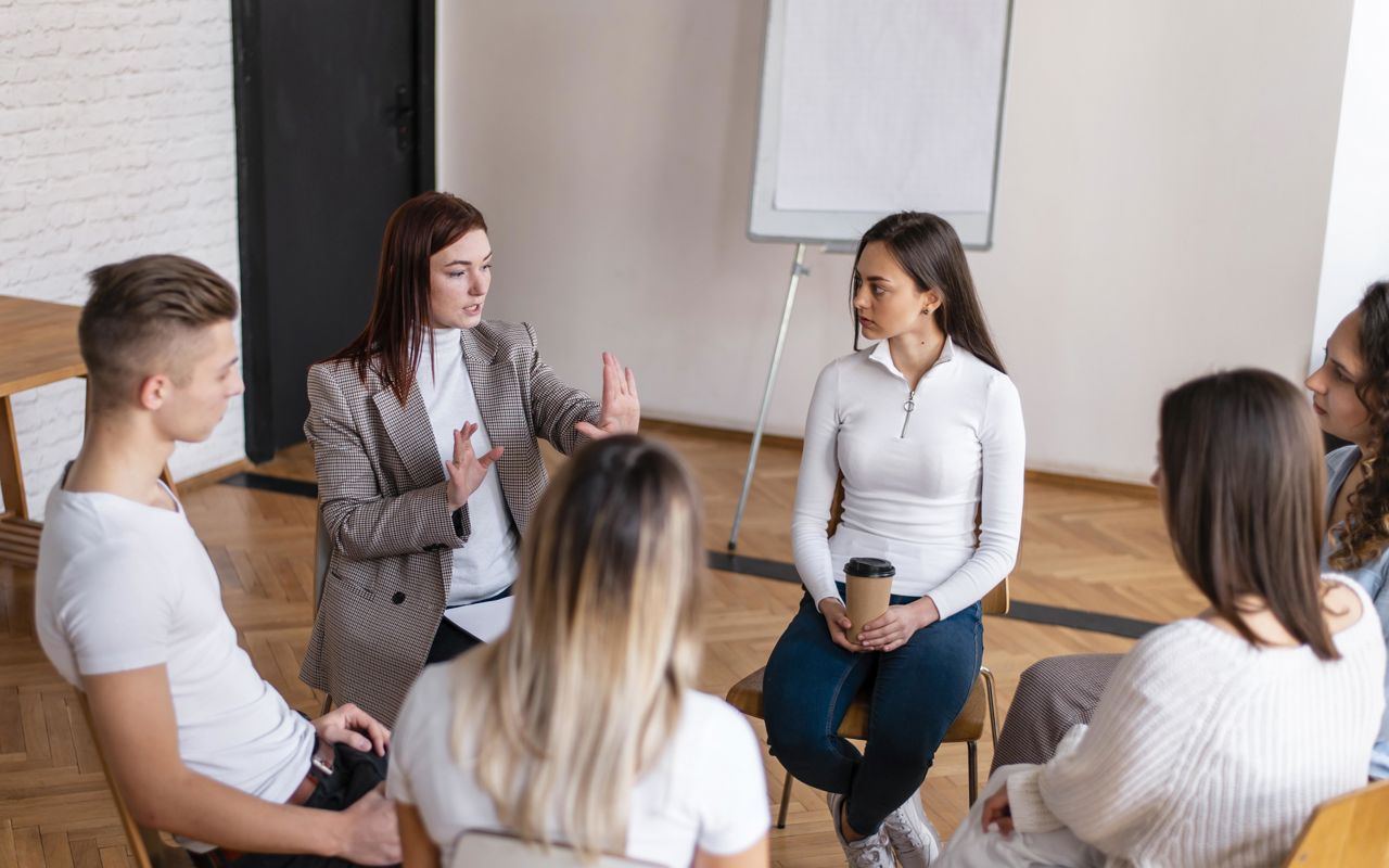 Unge siddende på stole i en rundkreds
