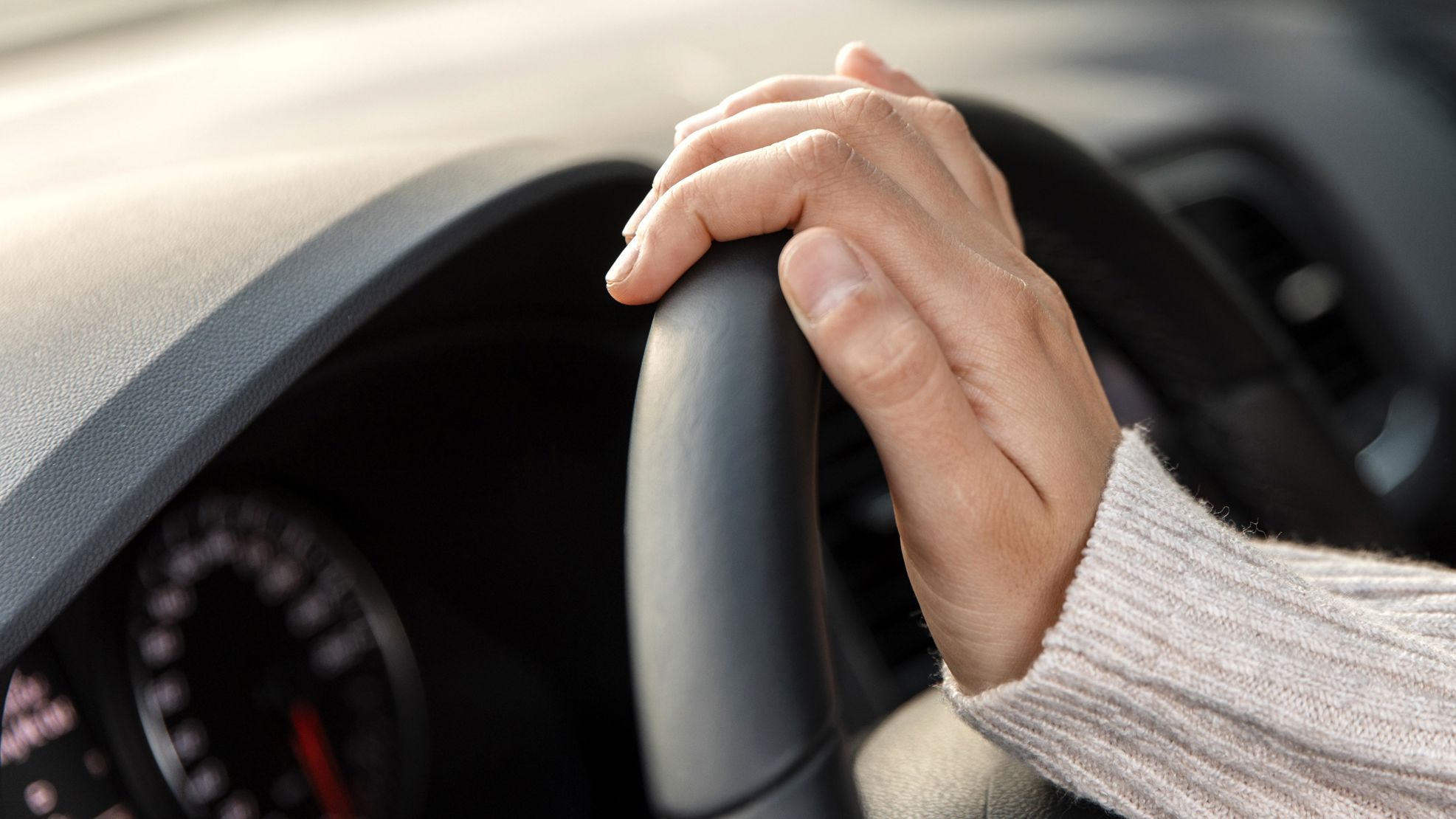Hånd på et bilrat i en bilkabine.