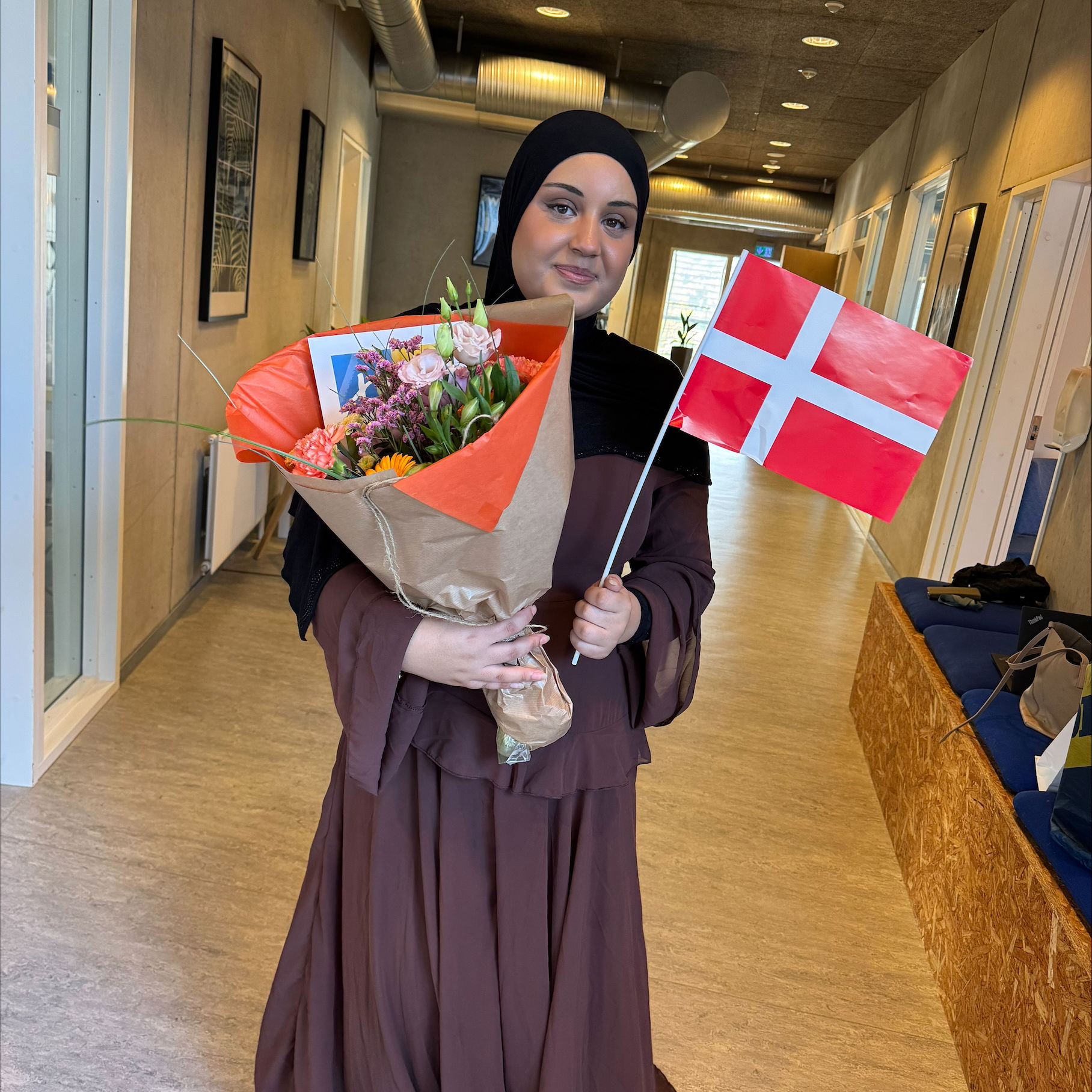 Fejring efter fagprøveeksamen juni 2026 på Campus Vejle - man ser Aja med blomst og flag