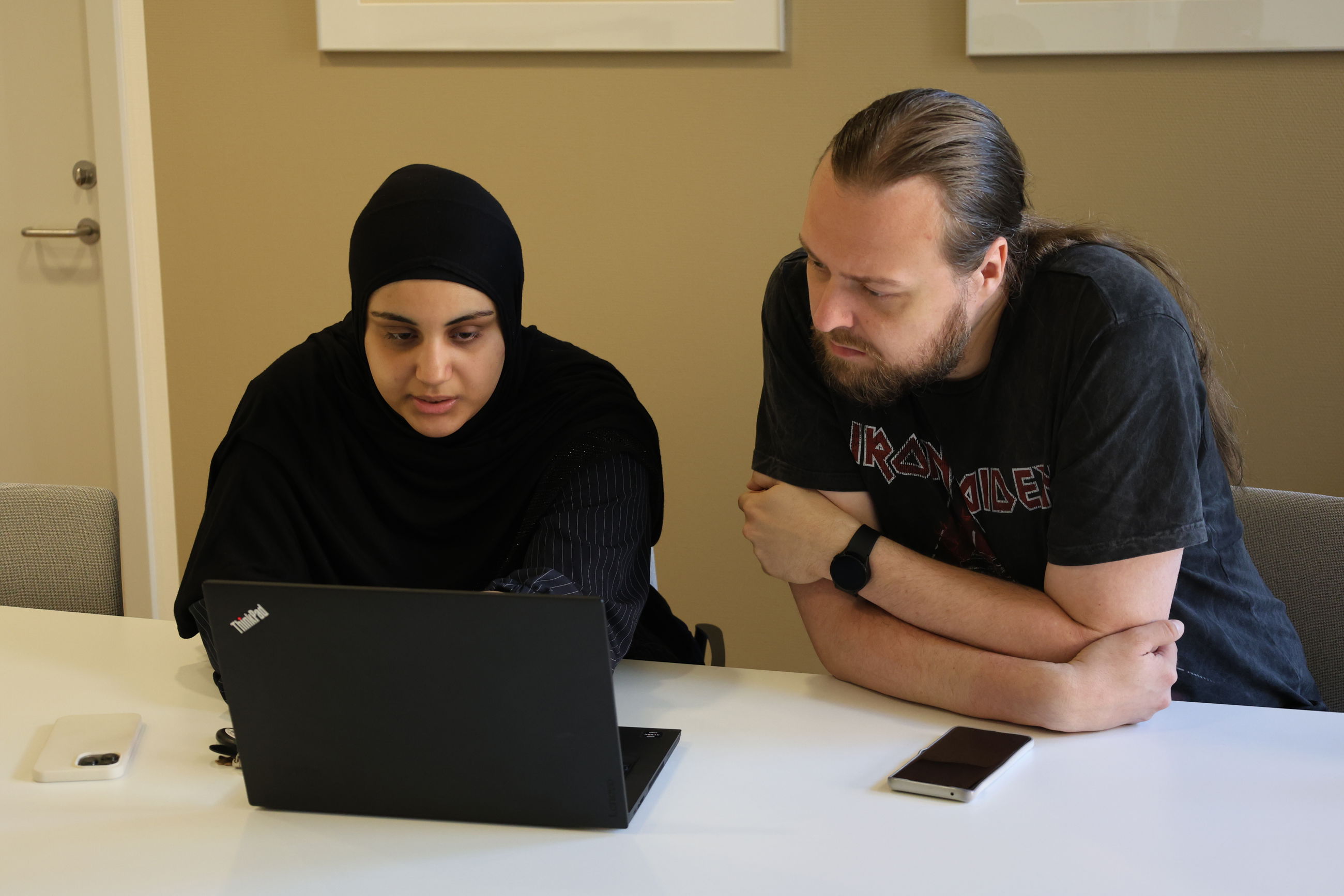 Kontoreleverne Aja og Mark arbejder koncentreret foran PC