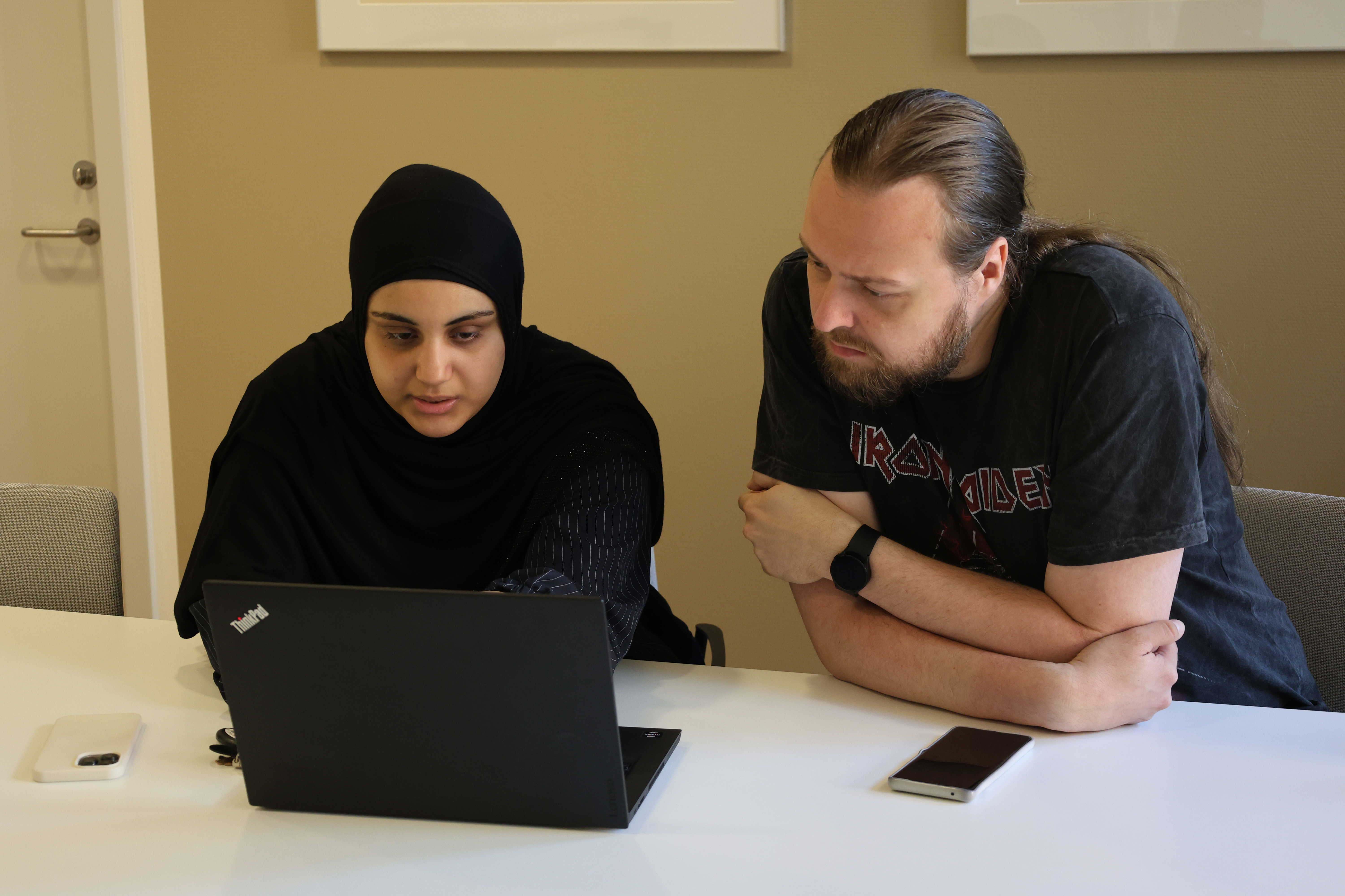 Kontoreleverne Aja og Mark arbejder koncentreret foran PC