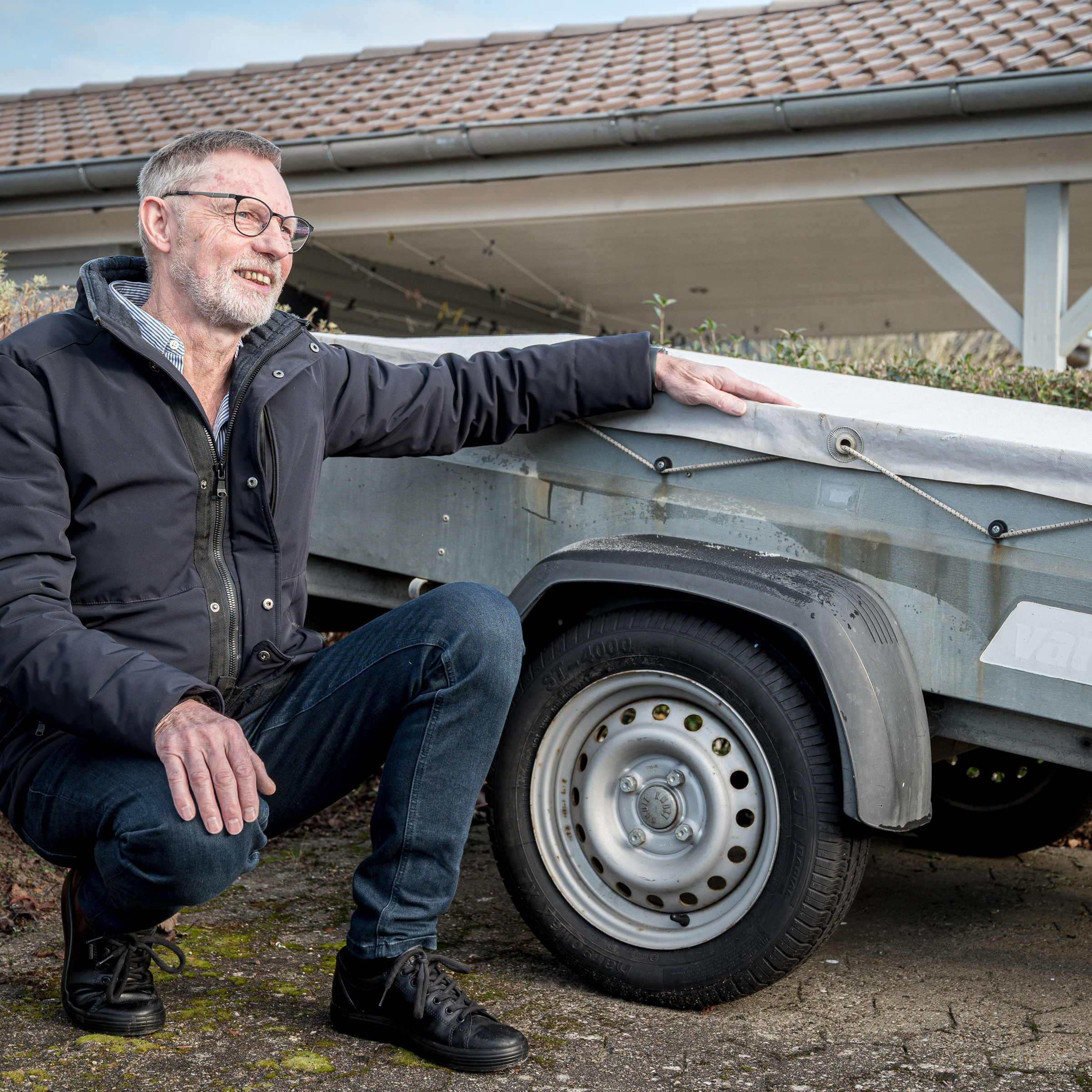 Allan Jensen fra Bredballe sidder på hug foran anhænger på det lille vænges fælles parkeringsplads.
