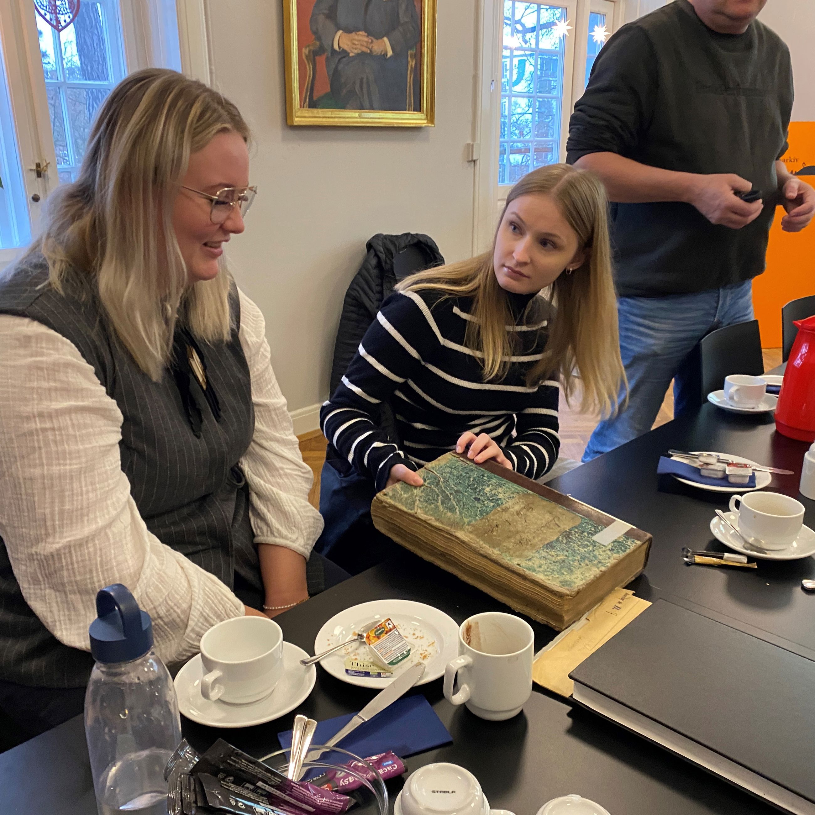 Signe og Frida med en gammel protokol fra besøg på Stadsarkivet