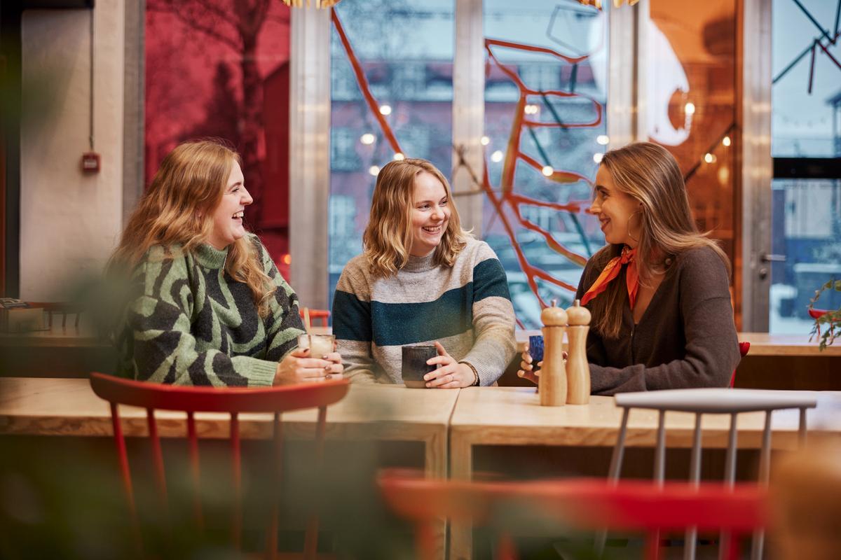 Tre kvinder drikker kaffe sammen i Spinderihallerne.