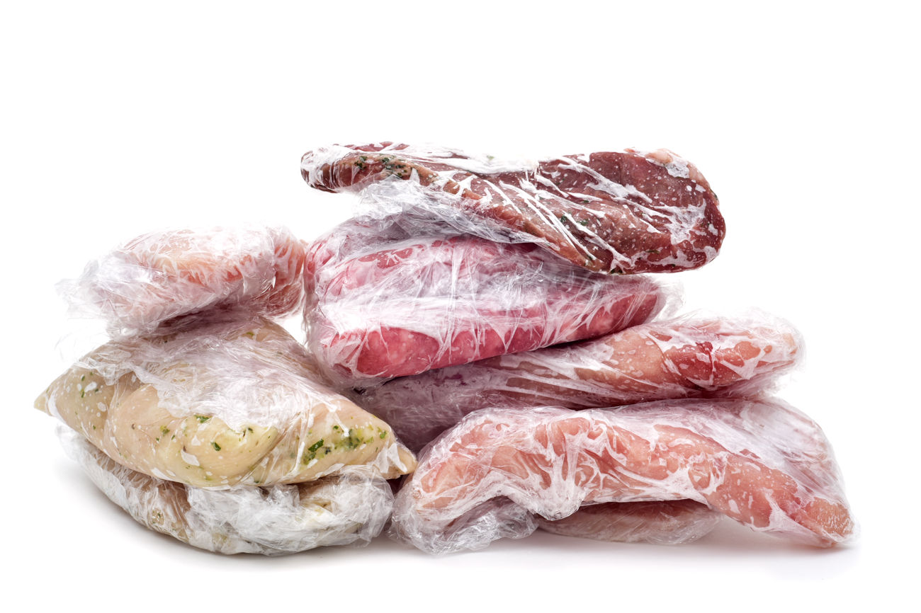 Forskellige typer frosset kød pakket i plast på hvid baggrund