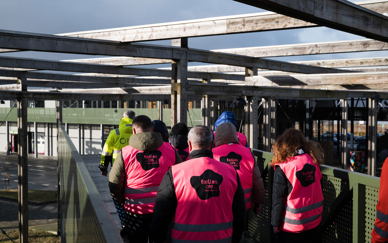 En gruppe mennesker iført pink sikkerhedsveste ses bagfra, mens de går rundt på Læringsbroen på RCV.