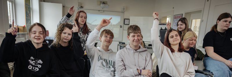 Unge der rækker hånden op i klasseværelse