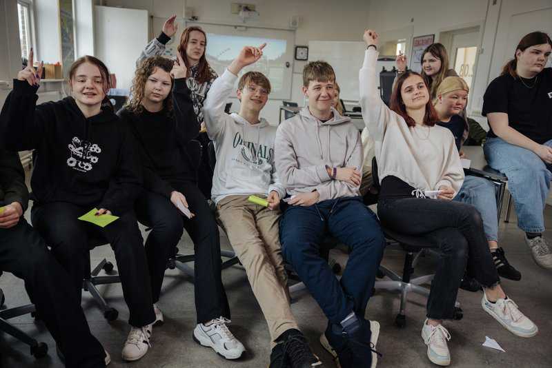 Unge der rækker hånden op i klasseværelse