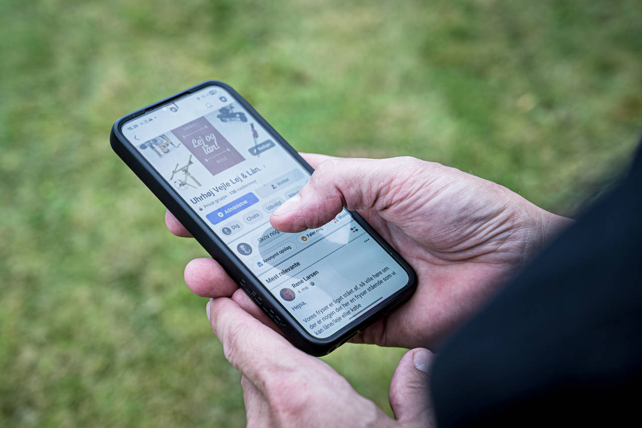 Nærbillede af en hånd, der holder en smartphone med Facebook-gruppen "Uhrhøj Vejle Lej & Lån" åben.