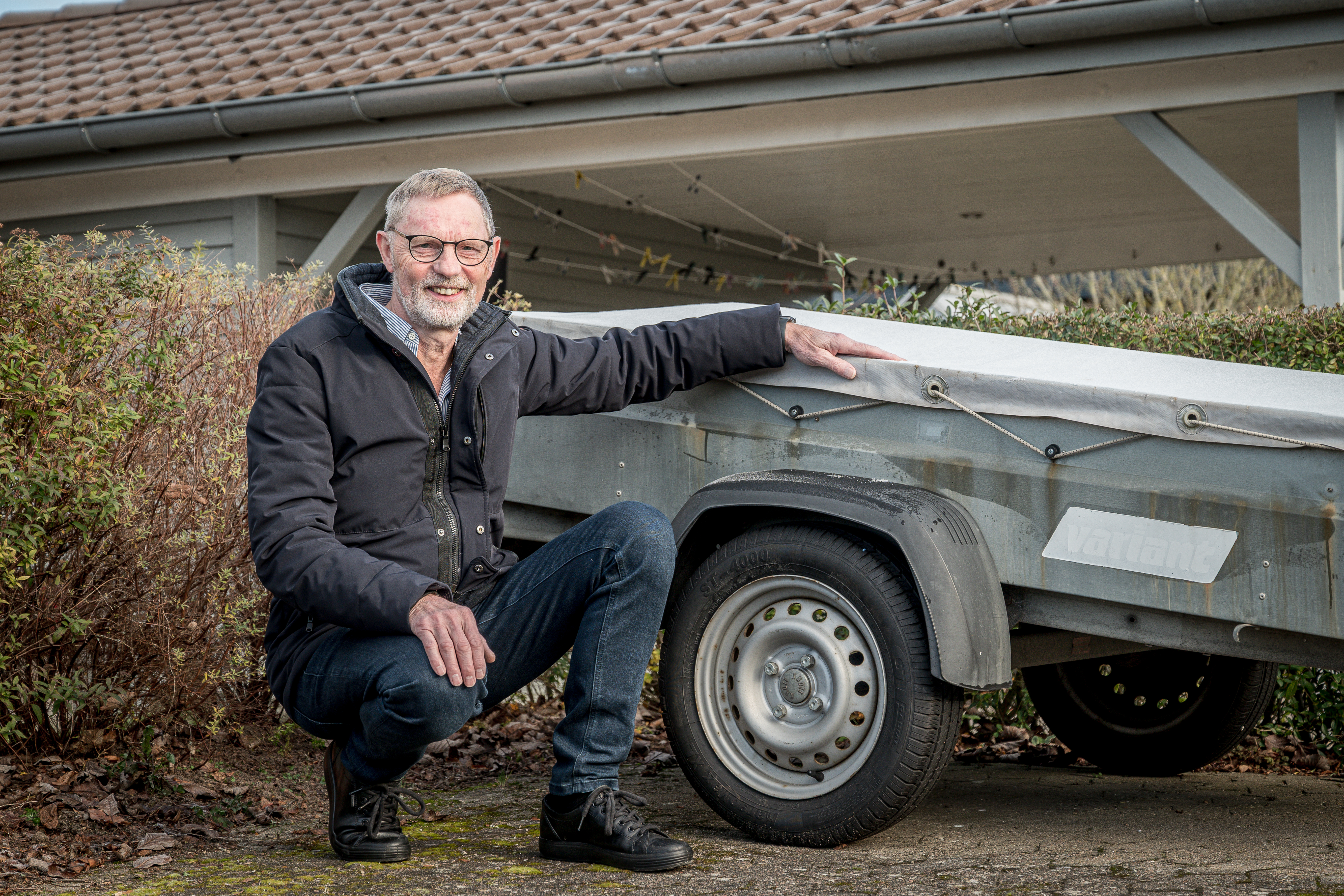 Allan Jensen fra Bredballe sidder på hug foran anhænger på det lille vænges fælles parkeringsplads.