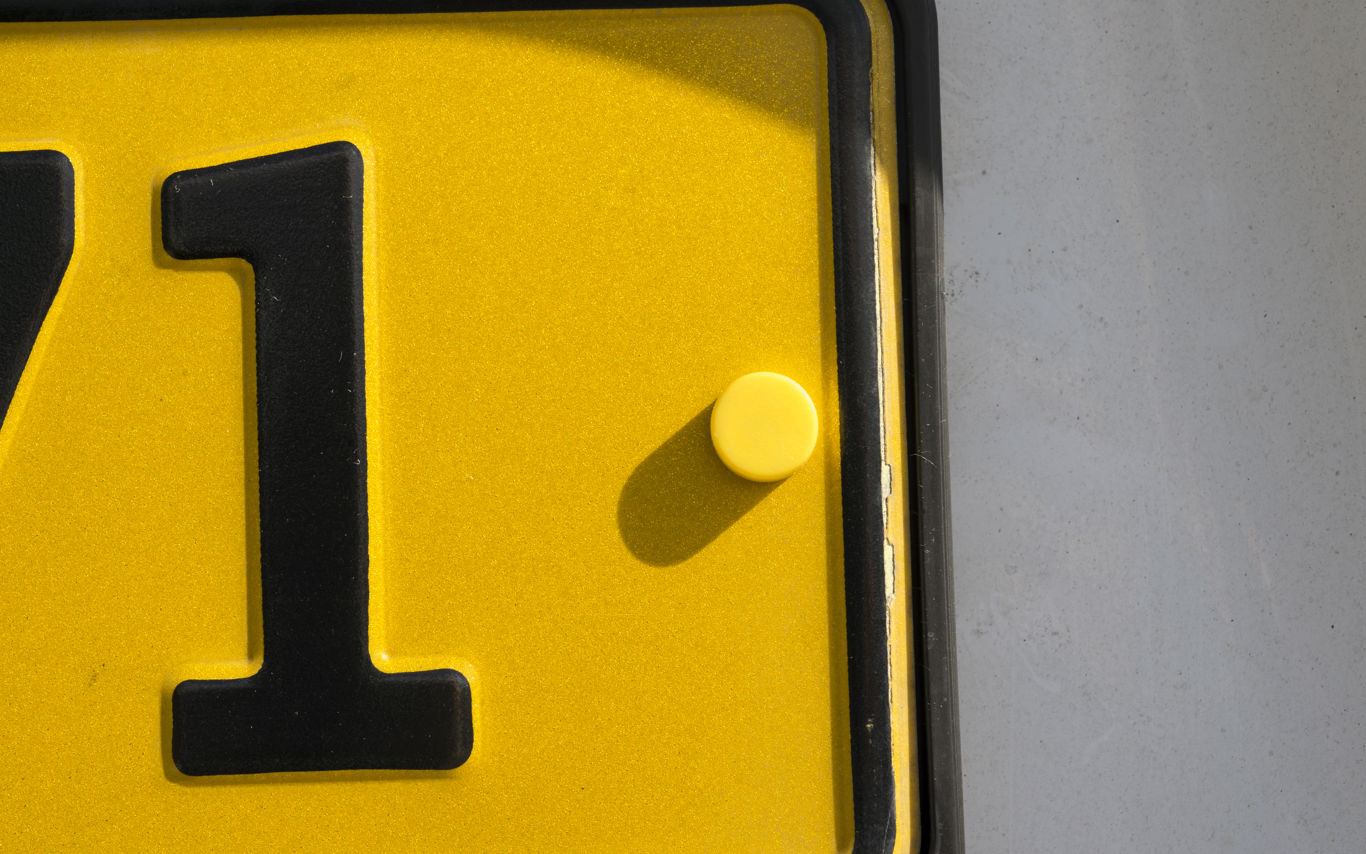 Et hjørne af en gul nummerplade med tallet 1.
