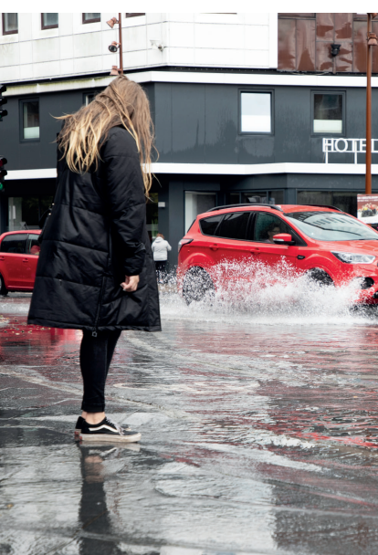 Biler der kører igennem en gade med højt vand
