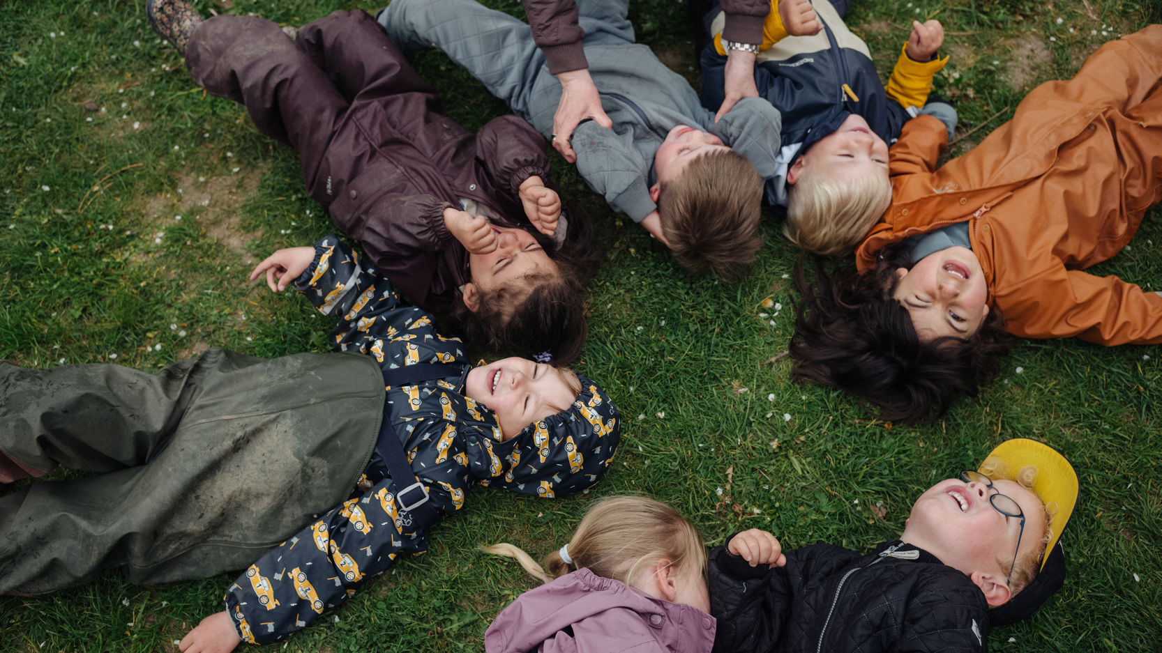 børn ligger på ryggen på græsset